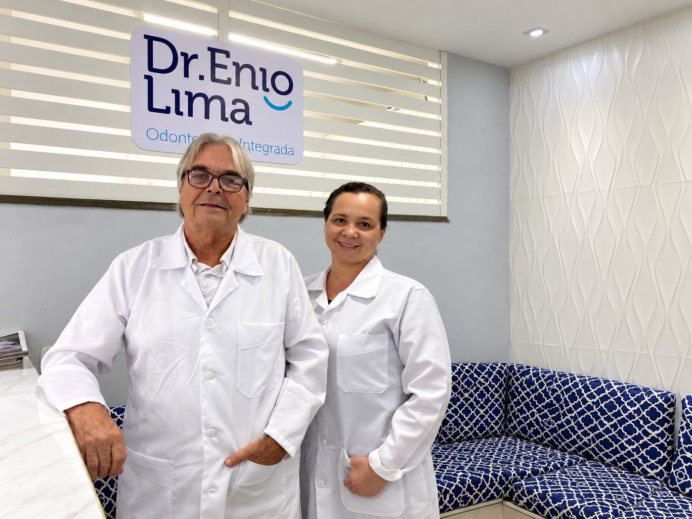 Dr. Robert e dentista da equipe na recepção, sob a placa Dr. Enio Lima Odontologia Integrada